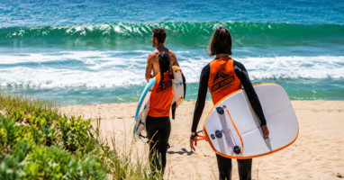 Twee surfsters lopen naar het strand in Peniche, Portugal – Clicktodo | فتاتان تحملان ألواح التزلج وتتجهان نحو شاطئ بينيش، ال